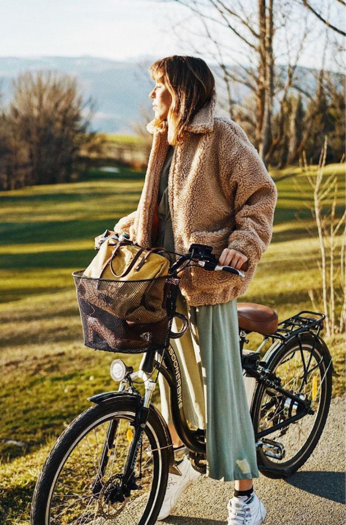 Bicyclette avec basket, femme en robe longue fluide et manteau fausse fourrure, tenue hiver femme moderne 