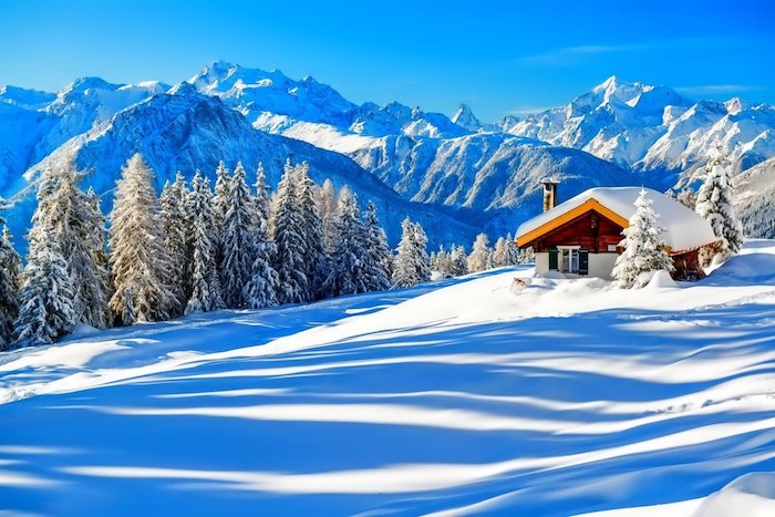 magnifique paysage alpestre avec chalet de montagne entourée de couche épaisse de neige, pics de montagne enneigés, sapins