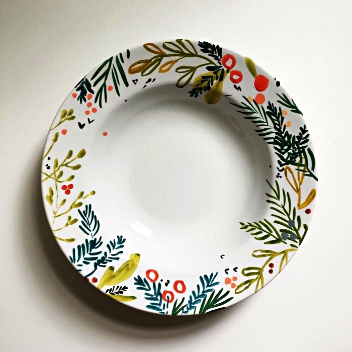personnaliser une assiette blanche avec de la peinture céramique, peindre des motifs végétaux sur une assiette pour un design de noël