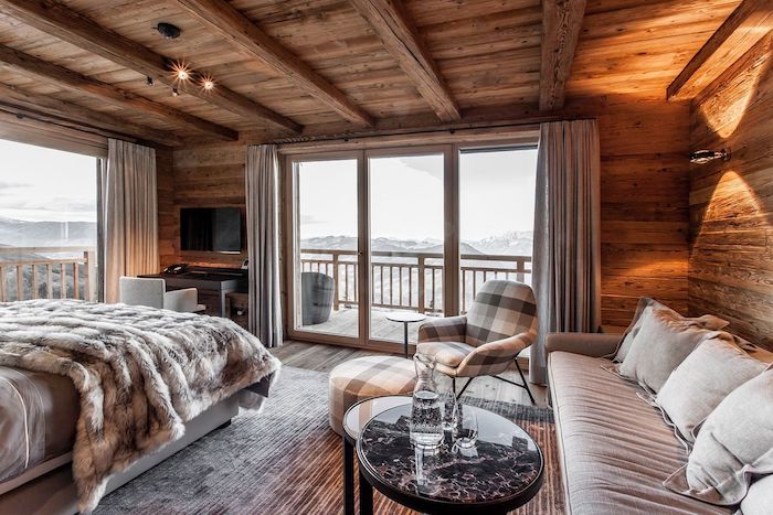 Chambre à coucher interieur chalet, déco chalet cosy chambre bois, confortable lit et coin de repos avec canapé, grande fenetre avec belle vue, balcon vue montagne