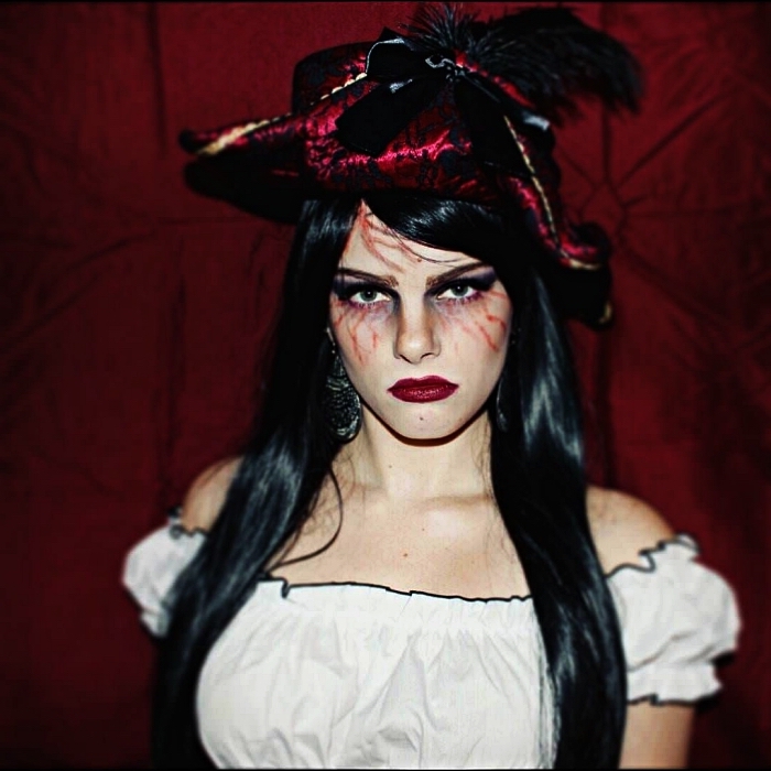 maquillage pirate femme créatif avec des veines dessinées autour les yeux, déguisement de pirate qui comprend un chapeau de fantaisie et un top aux épaules dénudées