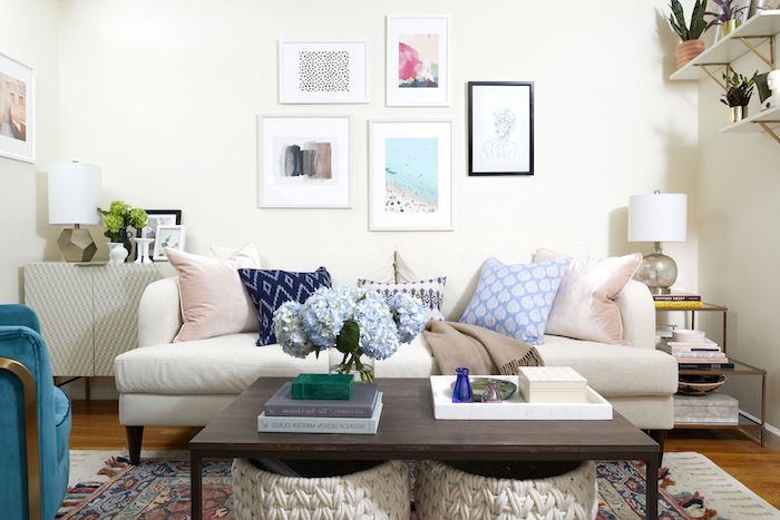 amenagement petit salon décoré avec canapé blanc décoré de coussins, table basse marron foncé, tapis coloré, bacs de rangement tressés