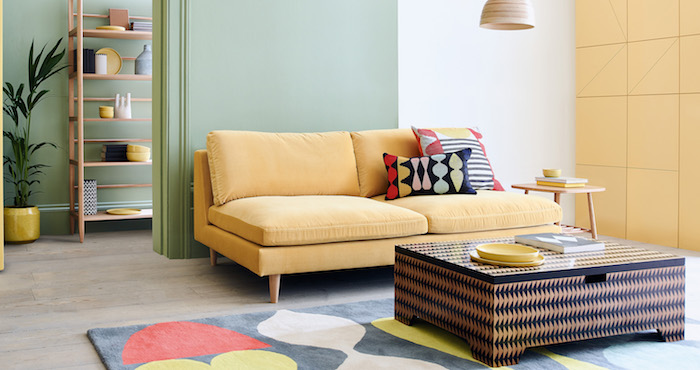 pan de mur jaune clair et pan de mur vert pistache, canapé jaune et tapis geometrique coloré, idee de salon pastel