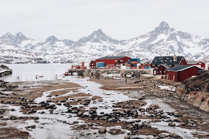 paysage nordique du pole nord, pics de montagne enneigés et plusieurs maisons nordiques couleur rouge, image fond ecran tres jolie