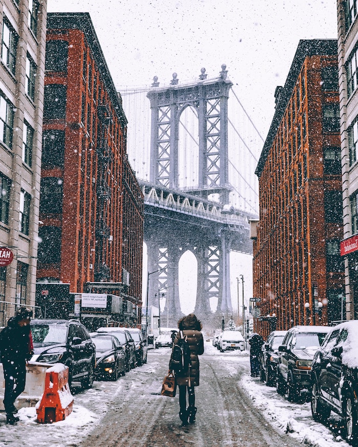 paysage urbain enneigé de la ville de new york avec batiments, rues enneigées et un grand pont entre deux batiments