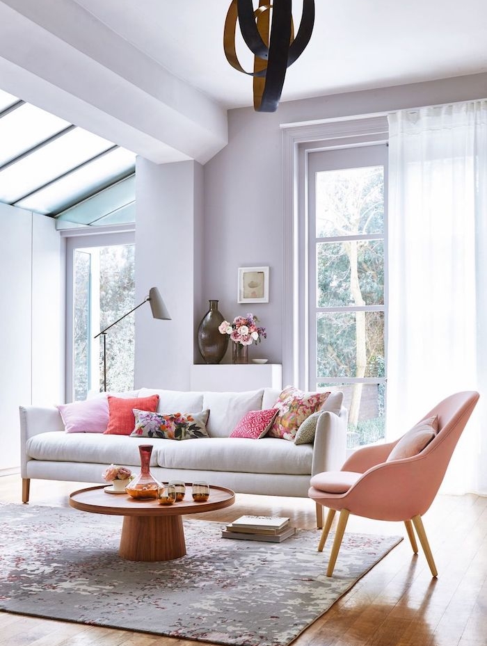 salon couleur mauve peinture lavande clair, canapé blanc, fauteuil rose, tapis gris sur sol décoré de parquet bois clair, suspension originale