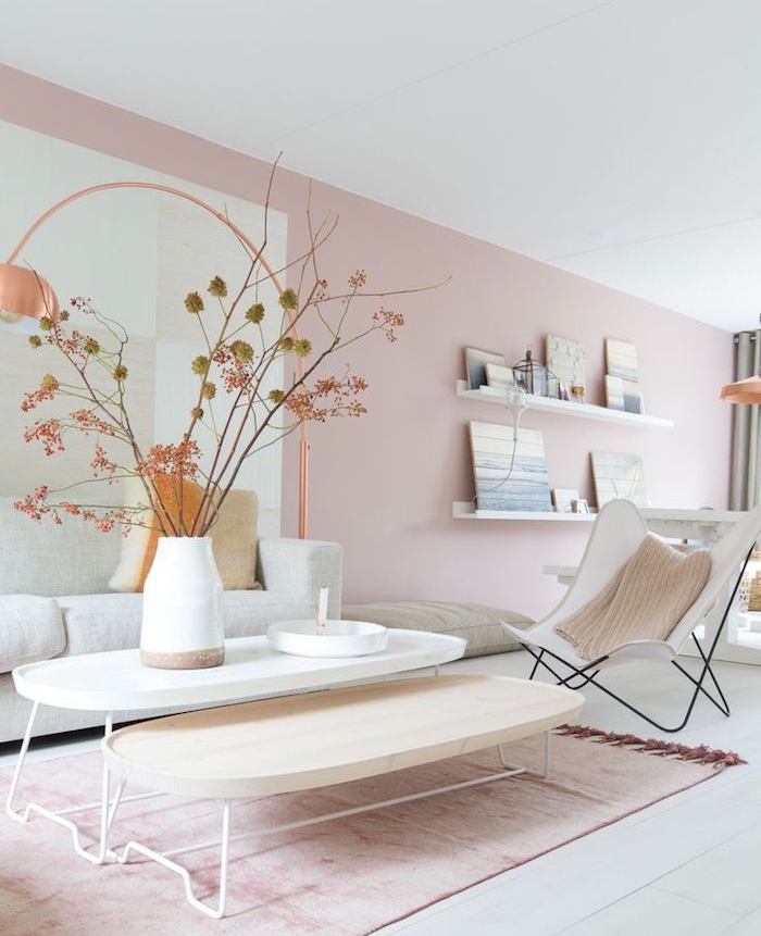 murs couleur rose clair et tapis rose clair sur parquet blanc, tables basses gigognes, chaise pliante blanche, vase rempli de branches d arbre