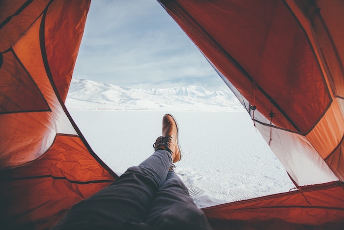 photo camping avec les james d une personne, selfie jambes dans une tente avec vue sur paysage enneigé desertique