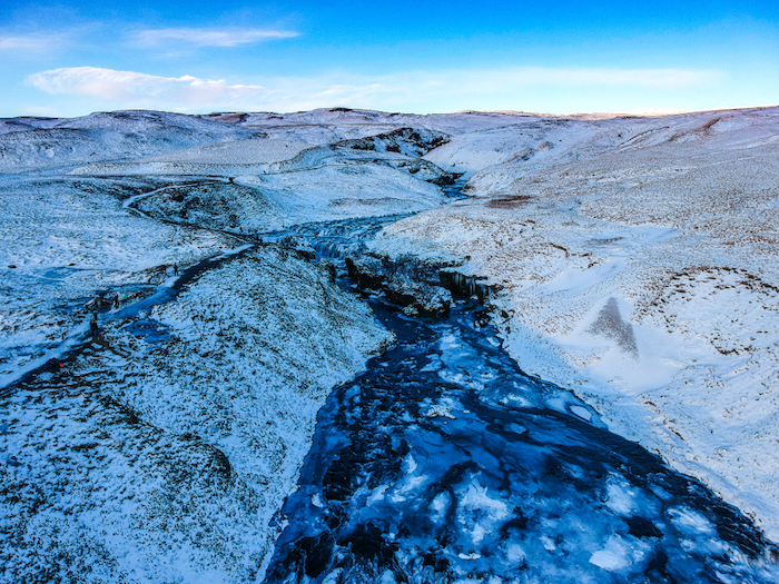 plaine enneigée avec une rivière glacée qui passe à travers, ciel bleu et blanc, fond ecran paysage desertique