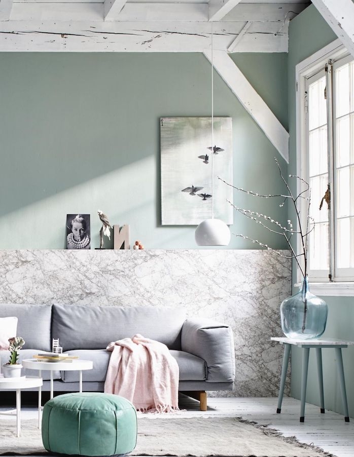 deco scandinave salon aux murs vert de gris et pan de mur effet marbre, tapis gris sur sol aprquet blanc, canapé gris clair, pouf vert d eau