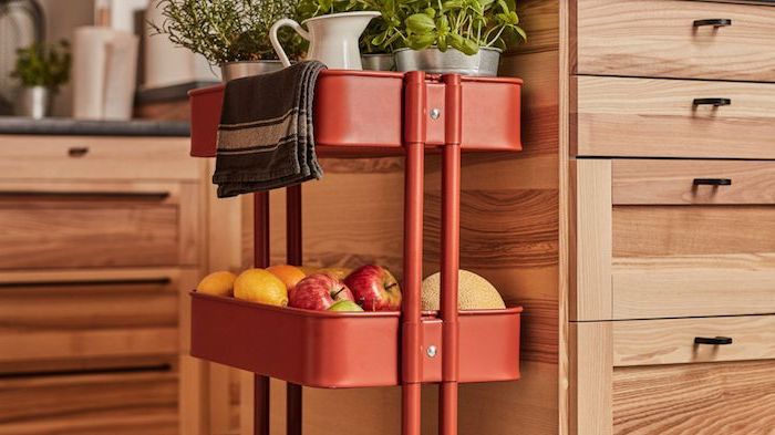 ranger fruits et herbes dans une cuisine sur desserte cuisine ikea de couleur rouge adossée à un ilot central en bois