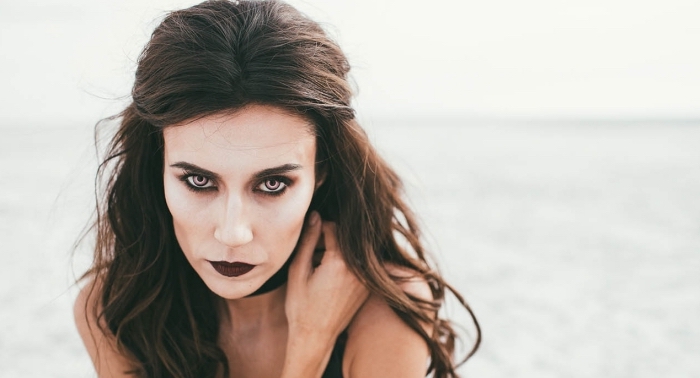 rouge-à-lèvre-noir-idée-maquillage-halloween-facile-deguisement-halloween-femme-en-vampire-cheveux-mi-attachés exemple de maquillage halloween simple à faire soi-même, maquillage vampire à fond de teint blanc et contouring visage