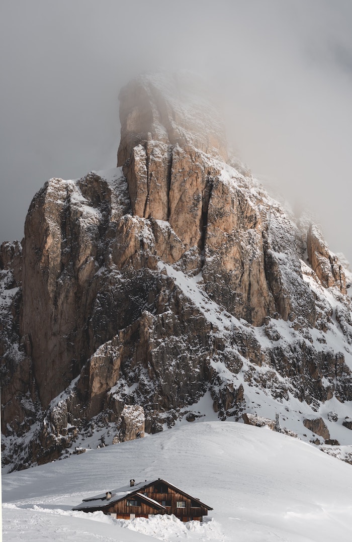 sommet de montagne rochet enneigé abrupte aux pieds d une colline et chalet de montagne bois enseveli sous la neige