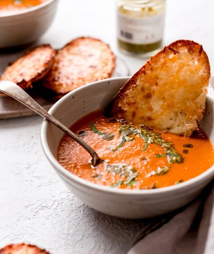 repas du soir léger avec oignons, tomates, carottes, soupe facile garnie de feuilles de basilic et toast aux fromages