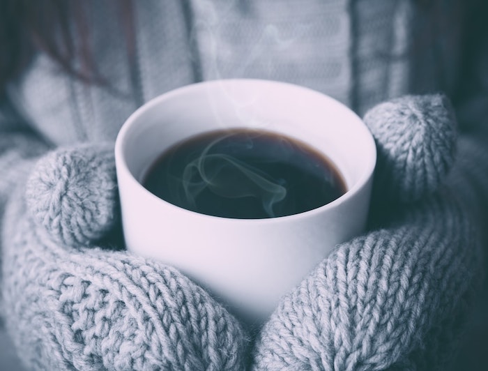 tasse de café entre mains gantés, exemple d image hiver cocooning de boisson chaude pour se chauffer en hiver