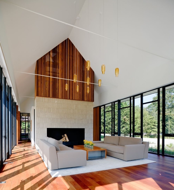 design intérieur stylé dans un salon à plafond haut avec grandes fenêtres, idée deco salon cosy en blanc et bois avec accents noirs