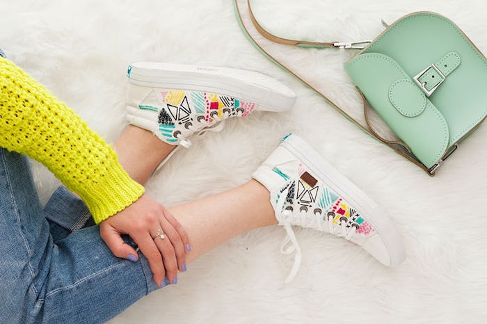Basket blanche personnalisé à l'aide de broderie coloré, savoir comment customiser ses chaussures, femme assise sur le sol portant jean slim et pull jaune