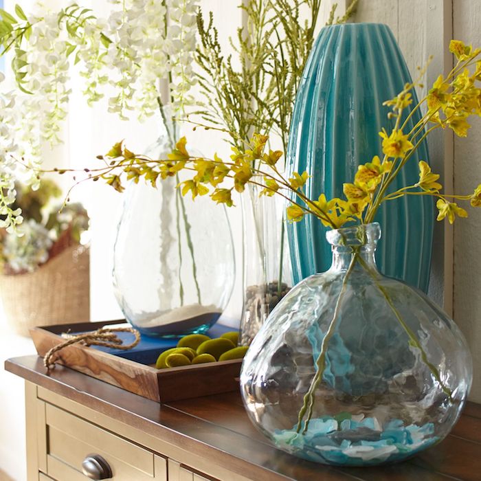 Printemps avec branches fleuries dans les vases diy, bonbonne en verre, intérieur design, superbe déco salon
