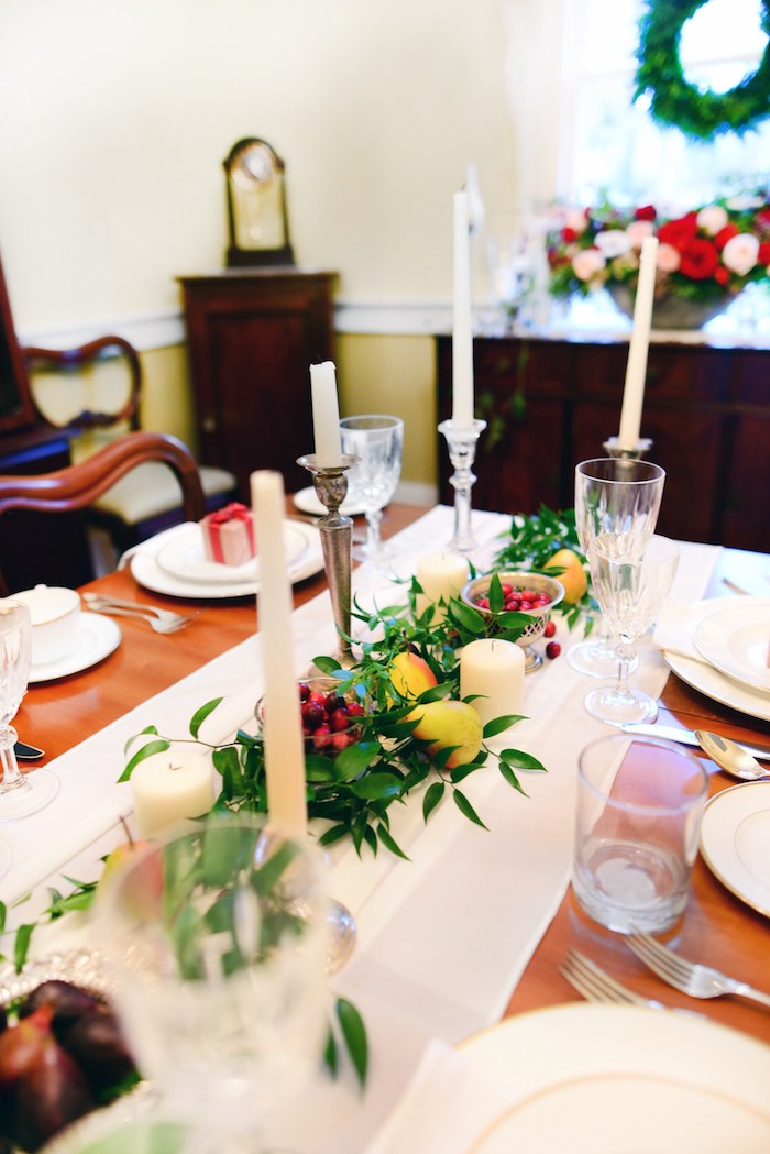 décoration de noël à faire soi même en chemin de table blanc décoré de feuillages verts, bougies blanches et fruits