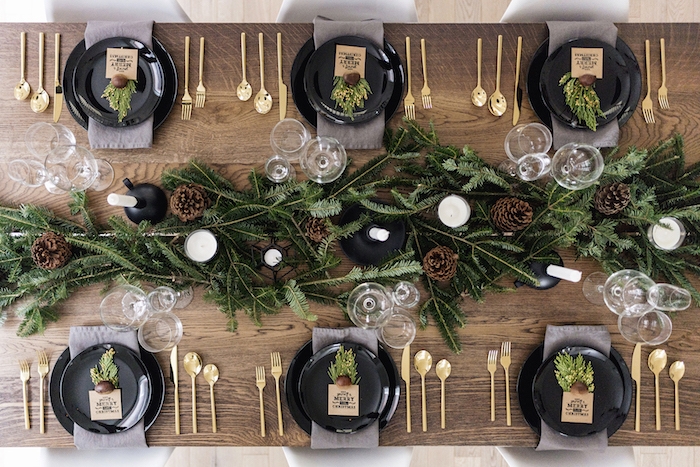 idee de deco table noel originale en bois avec des couverts de cuisine, centre en branches et pommes de pin, couverts en or