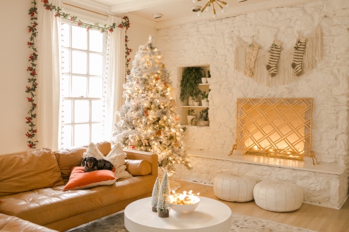 ambiance cocooning dans un salon blanc avec plancher bois et meuble en cuir camel, déco de Noël originale avec sapin de Noel blanc et gris
