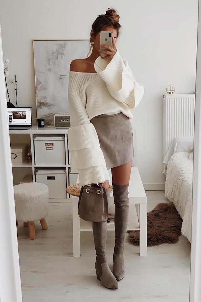Selfie dans le miroir de femme bien habillée en bottes cuissardes en velours, mini-jupe et blanc pull avec manches évasées 