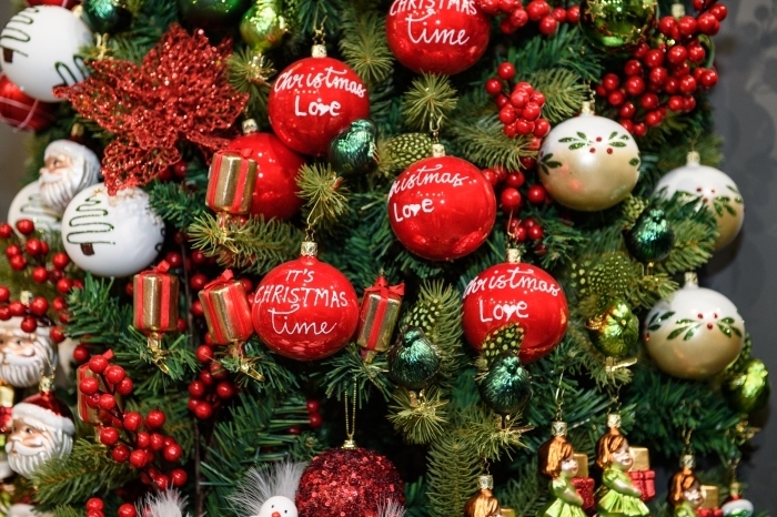 exemple comment décorer un arbre de Noël vert avec figurines à design tête père Noël et boules à message joyeux Noel