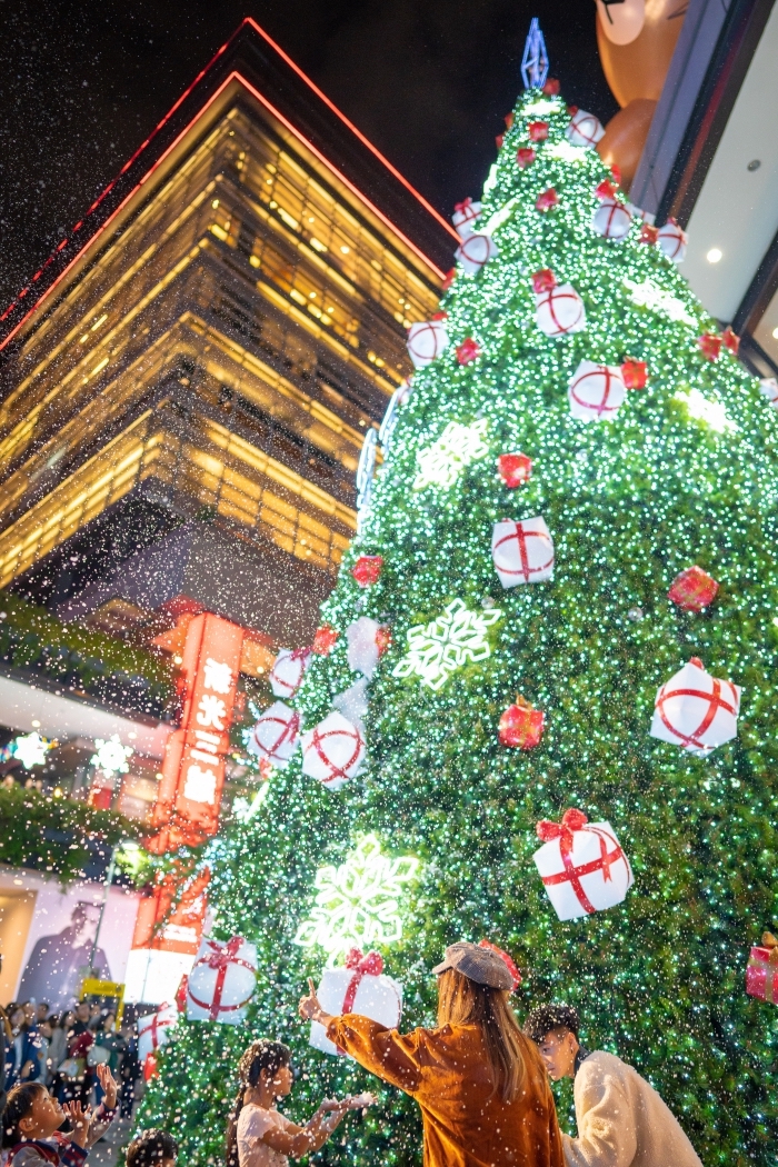 belle image de noel pour fond d'écran iphone, célébration fête de Noel au centre-ville devant un géant sapin décoré en vert et rouge