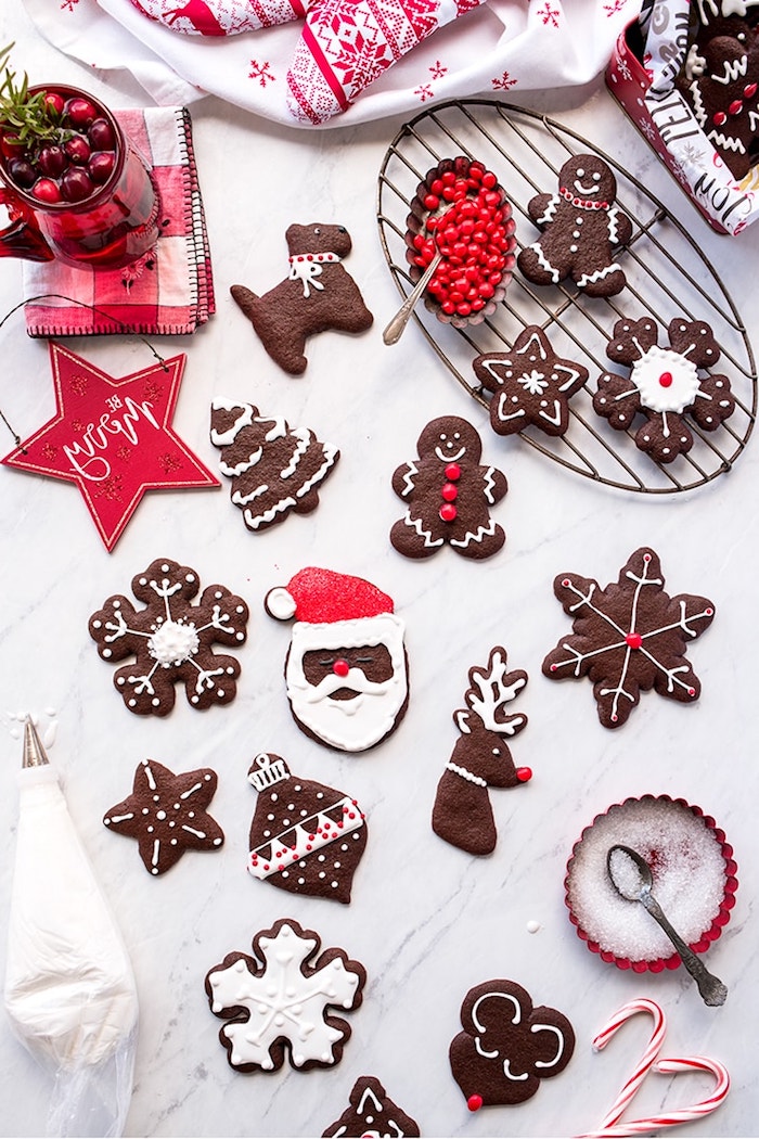 biscuit de noel au cacao avce glaçage royal blanc et deco rouge pour creer des motifs de sablés flocon d avoine, pere noel, renne de pere noel, etoile