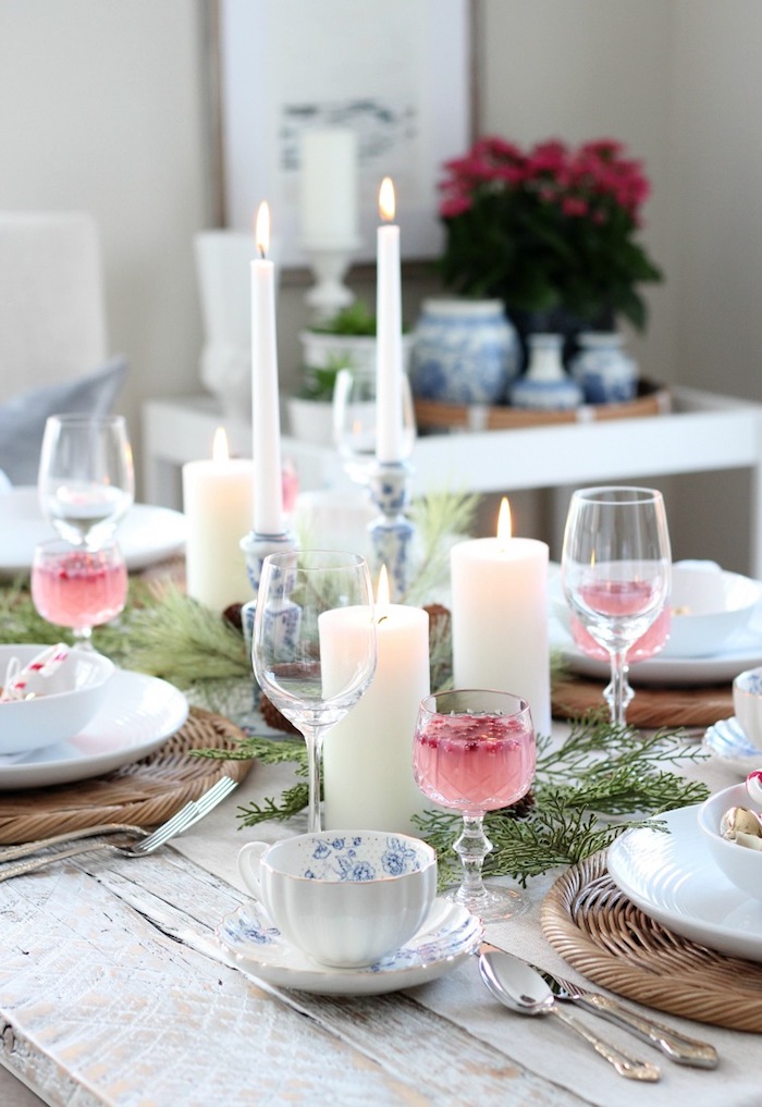 table campagne chic aux décoration de branches de pin, bougies blanches, dessous d assiette en bois