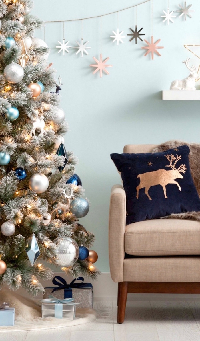 design intérieur moderne dans un salon aux murs bleu pastel aménagé avec meubles tissu et bois foncé, déco sapin de Noel avec ornements métalliques