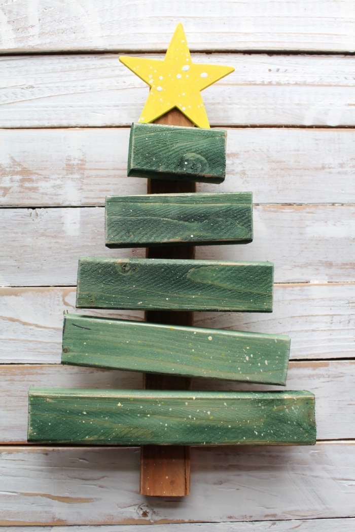 modèle de mini sapin fait main avec morceaux de bois recyclé repeint en vert et décoré avec une étoile jaune au sommet