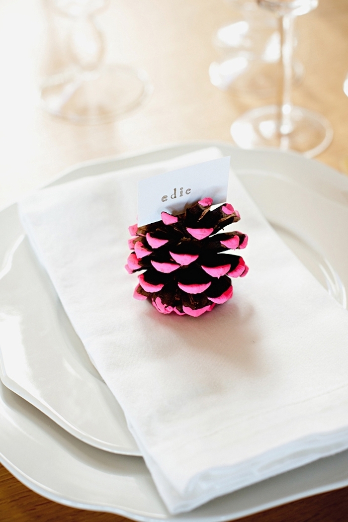 serviette blanche décorée de pomme de pin aux pointes roses avec étiquette prénom invité, deco noel diy simple