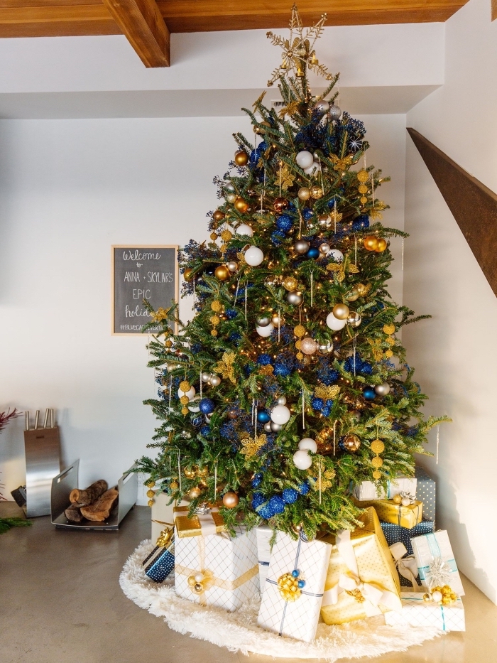décoration de Noël dans une pièce blanche avec plafond en bois et sol ciment, exemple de sapin de noel décoré en or et bleu