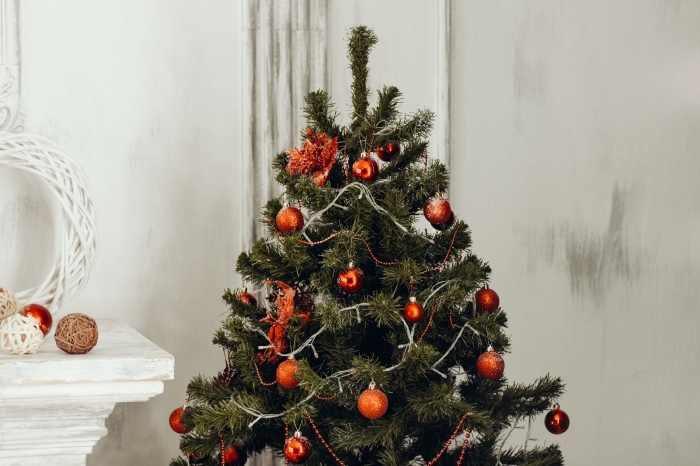 idee deco sapin de noel avec ornements rouges et guirlandes lumineuse, déco salon blanc pour Noël avec arbre de Noël artificiel
