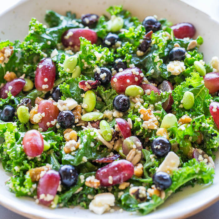 idée de salade chou frisé aux bleuets, haricots verts, quinoa, graines et des raisins frais dans une assiette
