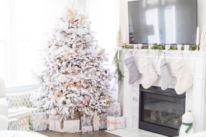 décoration cocooning dans un salon blanc pour Noël avec un gros arbre de Noël décoré en blanc et métalliques