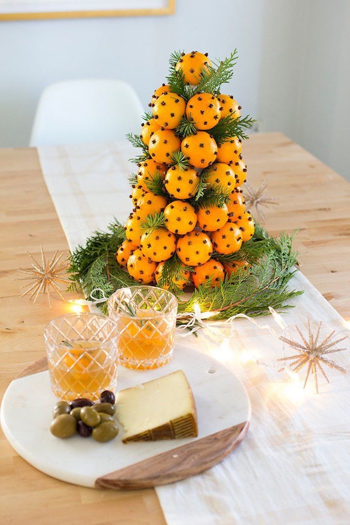 arbre de noel en mandarines et branches de pin décorées de girofle sur un chemin de table blanc, decoration de noel table