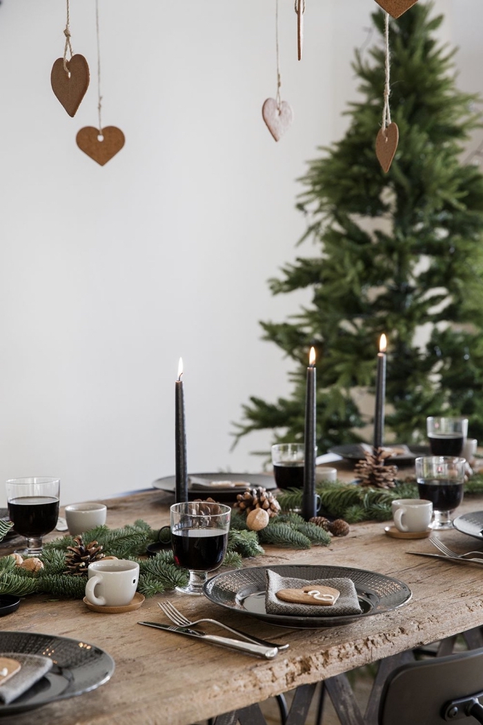 exemple comment décorer une table de style moderne avec objets en bois et noir mat, centre de table noel avec branches de sapin et bougies