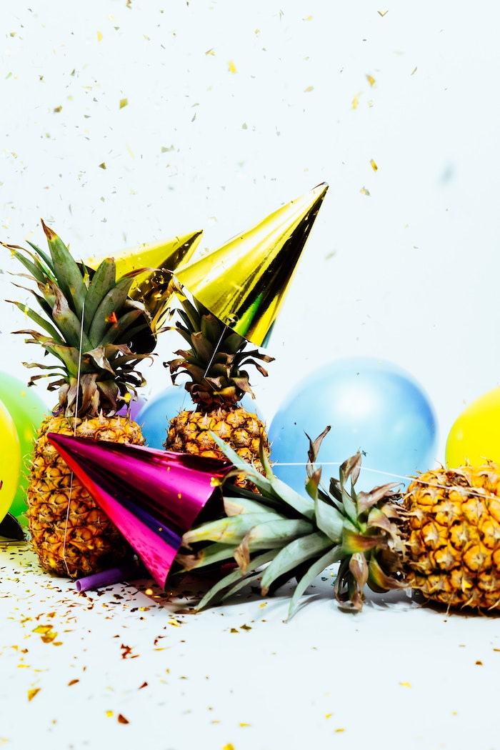decp ananas pour le jour de l an avec des ananas, ballons colorés et chapeaux de fete entourées de pluie de confettis