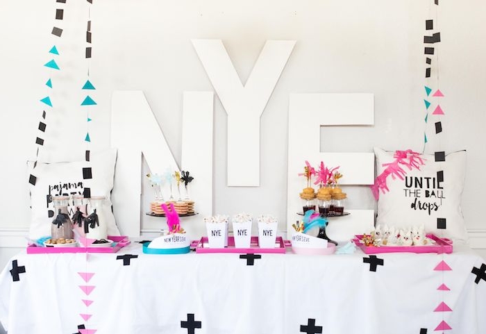 lettres nouvel an sur le fond, table avec plateaux de servie rose et bleu, guirlandes figures geometriques, mini pancakes candy bar de nouvel an