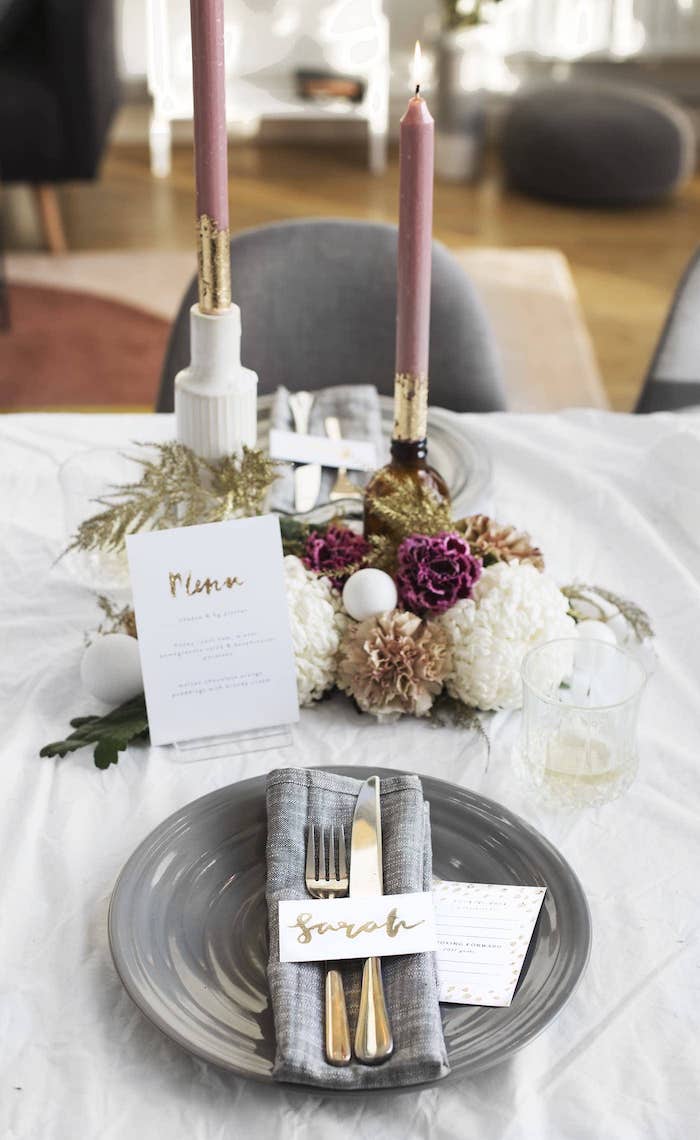 exemple deco table nouvel an avec assiette et serviette grise, centre de table bougies et bouquet de fleurs