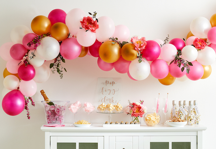 arche de ballons couleur blanc, or et rose au dessus d un buffet blanc avec candy bar barbe à papa, po corn, thème soirée cirque