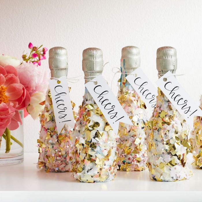 mini bouteilles de champagne décorées de confettis avec étiquette santé. petit bouquet de fleurs, decoration nouvel an 2020