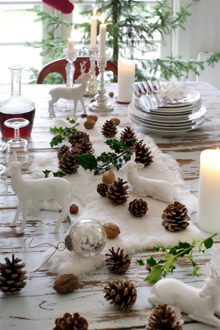 créer une déco de table cozy avec tapis blanc décoré de pommes de pin et figurines animalières, les plus belles tables de noel