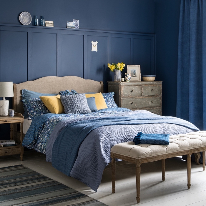 idée peinture bleu nuit dans une chambre aménagée avec meubles bois de style retro chic, déco de lit cocooning avec coussins et plaids en nuances de bleu