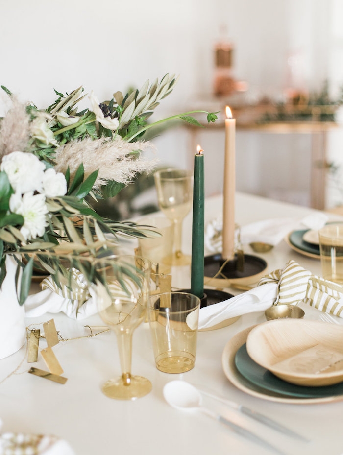 centre de table deco vegetale avec des verres en plastique, bougies vert et blanc cassé sur nappe blanche, assiettes de couleurs variées