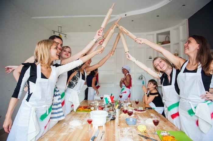 activité anniversaire entre amies idée cours culinaire cuisiner ensenble filles en tabliers blanches table bois farinée