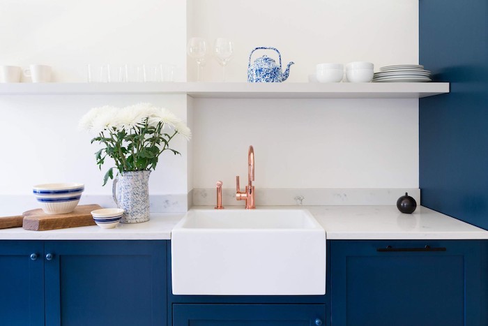 meuble bas bleu nuit et plan de travail marbre blanc, étagère blanche ouverte dans une cuisine pantone bleu et blanc, robinet cuivre