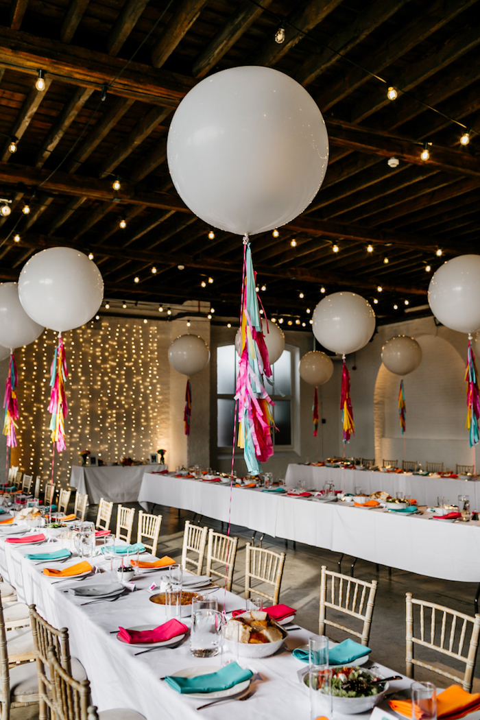 ballons blancs à l hélium avec décoration de chutes de papier coloré au dessus de table à nappe blanche déc0rée de serviettes multicolores